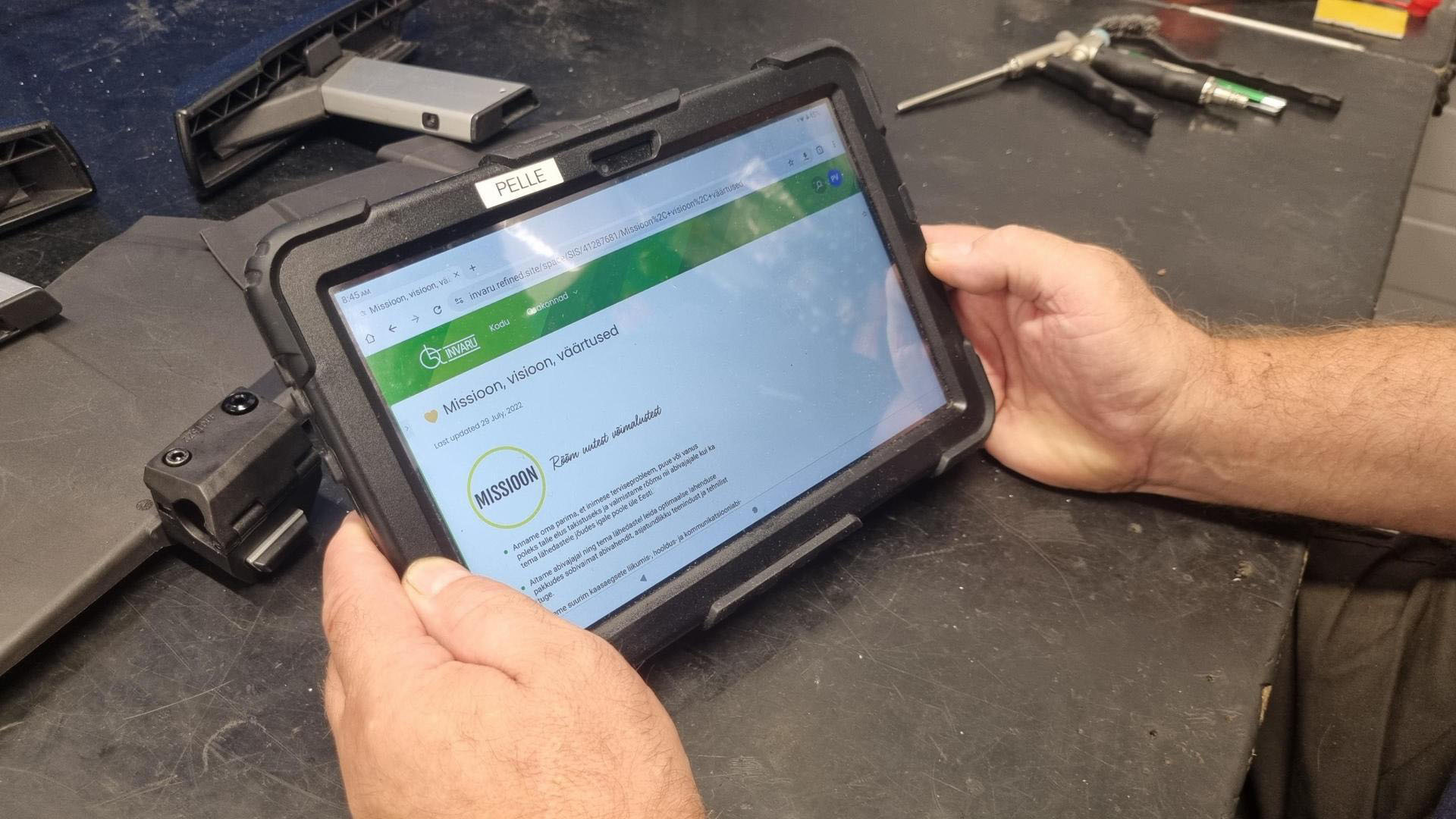 Picture of a mechanic holding a tablet to use intranet.