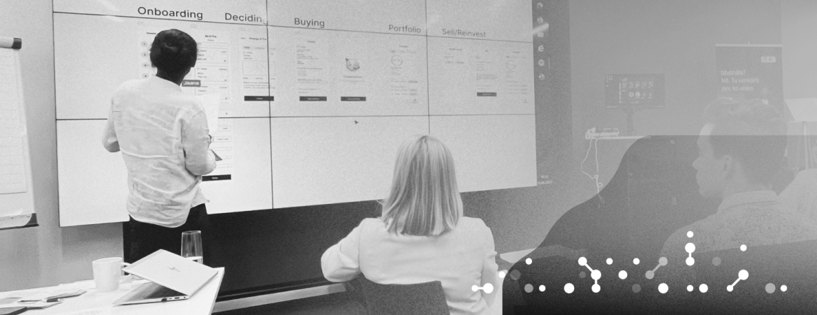 the project team in the meeting, the woman is sitting and the man is in front of the board